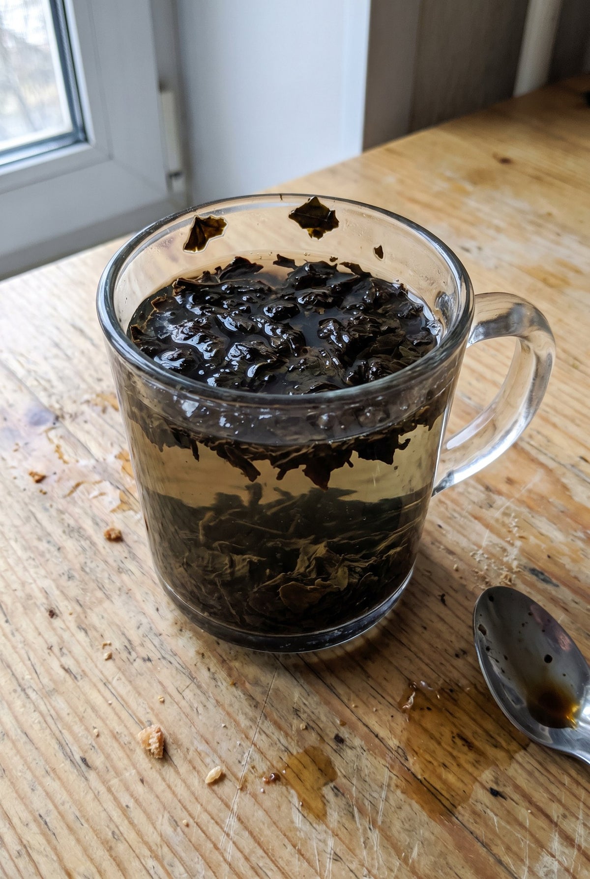 Une tasse de thé trop infusé, sombre et pleine de feuilles
